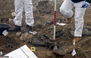 ICMP forensic experts stand near human remains during the exhumation of a mass grave believed to hold the bodies of massacre victims from the 1992-1995 war in Bosnia, in the village of Kozluk